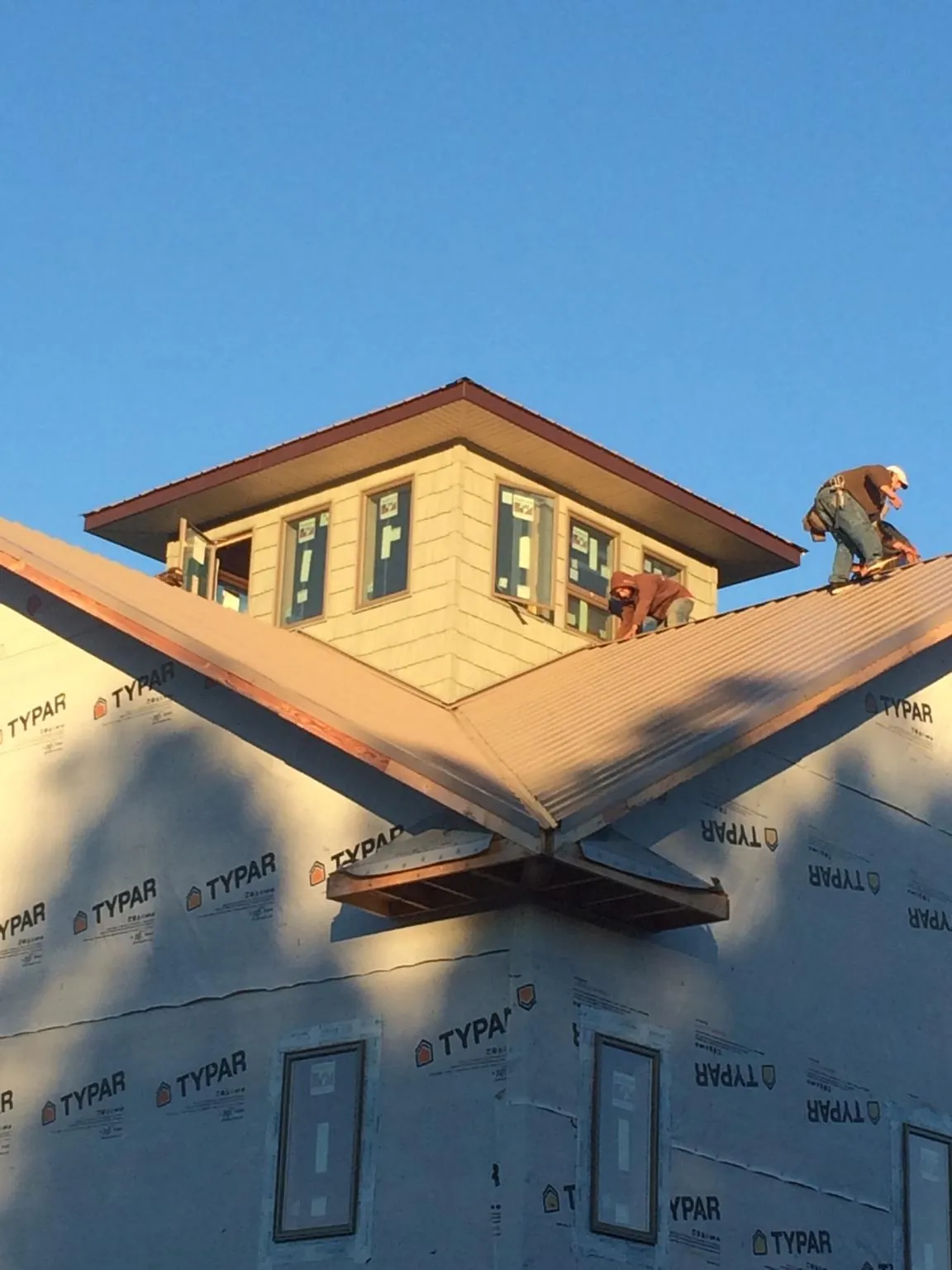 Roofers working around a rooftop cupola on a new metal roof at sunset — Roof Waterproofing in Jacksonville by Roofing Brothers